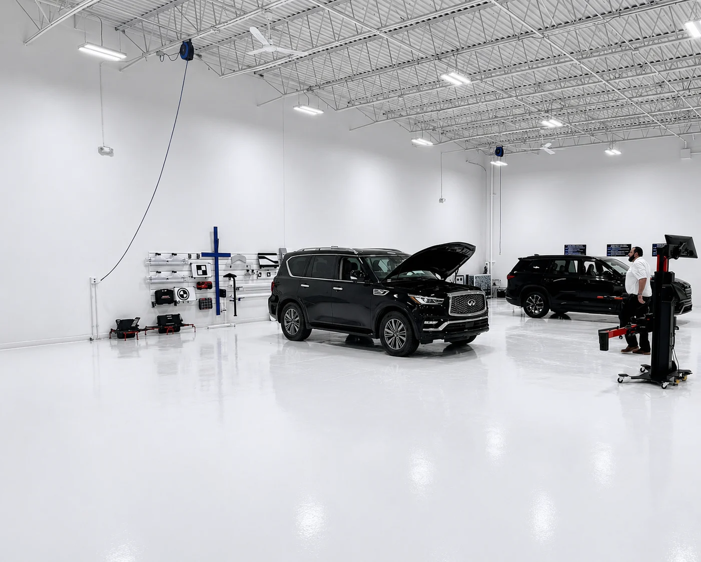 Multiple vehicles staged in a clean ADAS calibration bay with alignment equipment and technician