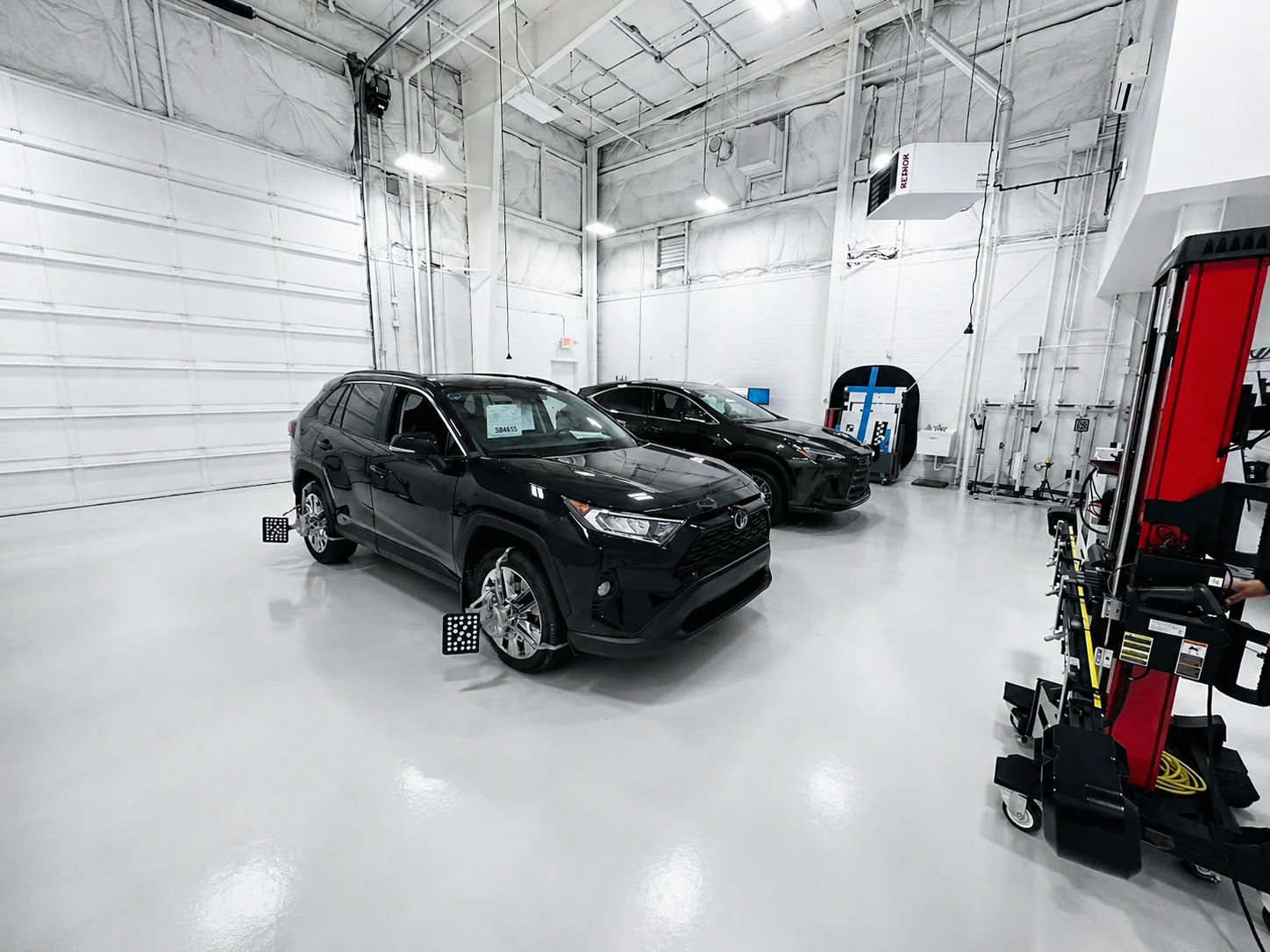 Vehicles positioned for ADAS calibration and alignment in a clean collision repair facility